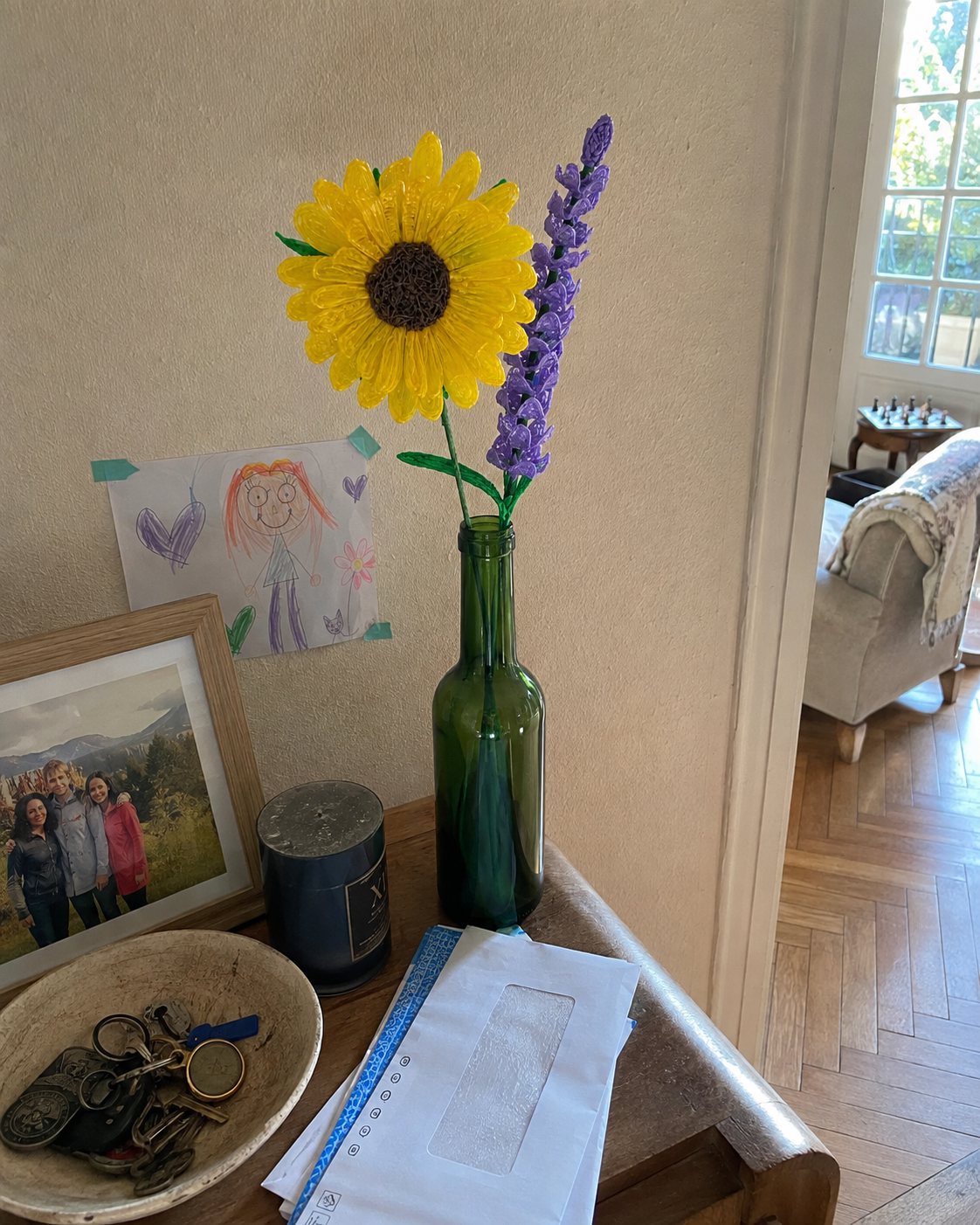 Un girasol y una ramita de lavanda en una botella de vidrio sobre un aparador